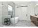 Modern bathroom featuring a soaking tub, glass shower, and sleek vanity with dark fixtures at 4604 W Lowell Ave, Tampa, FL 33629