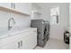 Laundry room features modern washer and dryer with white cabinets and a stainless steel sink at 4604 W Lowell Ave, Tampa, FL 33629