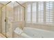 Relaxing bathroom features a soaking tub, a separate glass shower, and plantation shutters for privacy at 6208 Forrestal Dr, Tampa, FL 33625