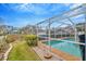 Sparkling screened-in pool area with lush landscaping, brick pavers, and a clear blue sky at 6208 Forrestal Dr, Tampa, FL 33625