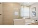Bright bathroom with a large glass-enclosed shower and luxurious soaking tub with elegant fixtures and artwork at 624 Maraviya Blvd, Nokomis, FL 34275