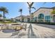 Community clubhouse exterior with outdoor fireplace and seating, surrounded by lush landscaping and palm trees at 624 Maraviya Blvd, Nokomis, FL 34275