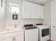 Functional laundry room with washer, dryer, sink, white cabinetry, and a window for natural light at 624 Maraviya Blvd, Nokomis, FL 34275
