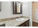 Bathroom featuring a decorative granite countertop, framed mirror, and wood cabinetry at 6580 Seminole Blvd # 417, Seminole, FL 33772