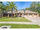 Charming one-story home with a three-car garage, brick accents, and a lush green lawn with beautiful palm trees at 70 Deerpath Dr, Oldsmar, FL 34677