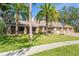 Home's front elevation features a three-car garage, lush lawn, mature landscaping and brick column accents at 70 Deerpath Dr, Oldsmar, FL 34677