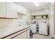 Bright laundry room with sink, counter space, storage cabinets and modern washer/dryer at 70 Deerpath Dr, Oldsmar, FL 34677