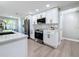 Bright, open kitchen featuring stainless appliances, modern white cabinets, and gray wood-look flooring at 9095 52Nd N St, Pinellas Park, FL 33782