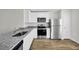 Modern kitchen featuring stainless steel appliances, granite countertops, and stylish wood flooring at 11073 Jackdaw Rd, Weeki Wachee, FL 34614