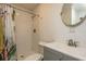 Bright bathroom featuring white tiled shower, gray vanity with round mirror, and decorative shower curtain at 2009 Douglas Ave, Dunedin, FL 34698