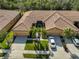 Aerial view of a home showcasing its stylish tile roof, attached garages, and well-manicured lawn at 320 Seneca Falls Dr, Apollo Beach, FL 33572