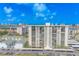 This is an eye-level drone shot of the high rise with a blue sky and waterfront backdrop at 400 Island Way # 305, Clearwater Beach, FL 33767