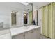 Bright bathroom featuring a light-gray vanity, decorative mirror, and a shower with modern tiles and a yellow curtain at 74 Gulf Blvd # 1B, Indian Rocks Beach, FL 33785