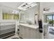 Bright bathroom featuring a light-gray vanity, decorative mirror, and a shower with modern tiles, and a view to the bedroom at 74 Gulf Blvd # 1B, Indian Rocks Beach, FL 33785