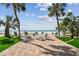 Seating area with beach access featuring palm trees and manicured green space at 74 Gulf Blvd # 1B, Indian Rocks Beach, FL 33785