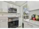 Modern kitchen with stainless steel appliances, white cabinetry, and access to an outdoor area at 74 Gulf Blvd # 1B, Indian Rocks Beach, FL 33785