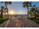 Serene beachfront patio featuring comfortable seating, palm trees, and picturesque ocean sunset views at 74 Gulf Blvd # 1B, Indian Rocks Beach, FL 33785