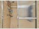 Shower with glass door, tan tile surround and multiple shower accessories at 74 Gulf Blvd # 1B, Indian Rocks Beach, FL 33785