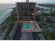 Aerial view of a beachfront condo with a pool deck and parking area next to a sandy beach at 7600 Bayshore Dr # 204, Treasure Island, FL 33706