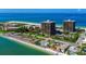 Stunning aerial view showcases beachfront condos, tennis courts, and crystal-clear turquoise waters at 7600 Bayshore Dr # 204, Treasure Island, FL 33706