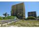 Beachfront condo buildings with balconies, accessible via a wooden walkway through lush vegetation at 7600 Bayshore Dr # 204, Treasure Island, FL 33706