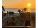Balcony with a picturesque view of the ocean at sunset, featuring palm trees and nearby buildings at 7600 Bayshore Dr # 204, Treasure Island, FL 33706