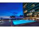 Outdoor pool illuminated at night with modern condos in the background, set against a twilight sky at 7600 Bayshore Dr # 204, Treasure Island, FL 33706