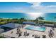 Outdoor pool deck with ocean views featuring lounge chairs, tables, and palm trees at 7600 Bayshore Dr # 204, Treasure Island, FL 33706