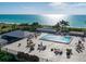 Outdoor pool deck with ocean views featuring lounge chairs, tables, and palm trees at 7600 Bayshore Dr # 204, Treasure Island, FL 33706