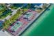 Aerial view featuring waterfront tennis courts, mature palm trees, and crystal-clear blue waters at 7600 Bayshore Dr # 204, Treasure Island, FL 33706