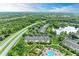Expansive aerial view showcasing the townhomes, community pool, and tranquil lake within a lush, green landscape at 8926 Manor Loop # 207, Lakewood Ranch, FL 34202