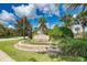 Welcoming entrance to the neighborhood featuring a sign with lush landscaping, palm trees, and an American flag at 8926 Manor Loop # 207, Lakewood Ranch, FL 34202