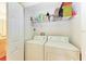 Functional laundry room with a washing machine, dryer, and shelving for storage, making laundry chores easier at 8926 Manor Loop # 207, Lakewood Ranch, FL 34202