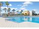 A community pool area is seen with a recreation center and pool furniture; palm trees add to the scenery at 9705 Runaway Breeze Dr, Land O Lakes, FL 34637