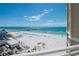 Gorgeous beach view from a balcony, highlighting white sands, blue umbrellas and a fishing pier at 10 Papaya St # 1404, Clearwater Beach, FL 33767