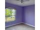 This bedroom is painted a beautiful purple and features tile floors and a window with a view at 10127 Barnett Loop, Port Richey, FL 34668