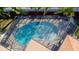 An aerial view of the screened-in pool showcases a clear water and a clean outdoor recreation space at 112 Forest Cir, Safety Harbor, FL 34695