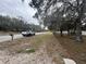 Street view with mature trees, a passing truck, and glimpses of the property's chain-link fence at 12205 Greenland Dr, Riverview, FL 33579