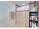 Shower with sliding curtain, adjacent to a storage cabinet and white paneled door at 12239 Fawn Brindle St, Riverview, FL 33578