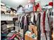 Walk-in closet is full and slightly disorganized; contains a variety of clothing items and storage containers on shelving at 12239 Fawn Brindle St, Riverview, FL 33578