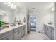 Bright bathroom featuring a double sink with gray cabinets, and a doorway to a bedroom at 12829 Tortoise Shell Pl, Riverview, FL 33579