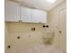 Functional laundry room with white cabinets, utility sink, and tile flooring at 13128 Hazelcrest St, Spring Hill, FL 34609