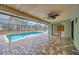 Covered patio with ceiling fan overlooks the screened pool and brick-paved deck, enhancing outdoor living at 13128 Hazelcrest St, Spring Hill, FL 34609