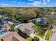 Scenic aerial view of a home in a tree-lined neighborhood, with a pool, lawn, and shaded streets at 15109 Winterwind Dr, Tampa, FL 33624