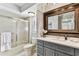 Bathroom featuring shower over tub with glass doors, vanity and large framed mirror at 15109 Winterwind Dr, Tampa, FL 33624