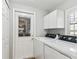 Well-equipped laundry area with white cabinets, modern appliances, and a convenient door to the outside at 15109 Winterwind Dr, Tampa, FL 33624