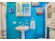 Charming bathroom featuring a pedestal sink, bright blue walls, and decorative wall art at 18675 Us Highway 19 N # 320, Clearwater, FL 33764