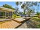 Spacious backyard with a wooden deck, screened porch, and lush greenery at 2008 Harvard Ave, Dunedin, FL 34698