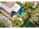 Aerial view of the property showcasing the pool, patio, and surrounding lush landscaping at 2460 Baywood E Dr, Dunedin, FL 34698