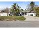 Charming single-story home with tropical landscaping, white picket fence, and a welcoming screened-in porch at 2460 Baywood E Dr, Dunedin, FL 34698